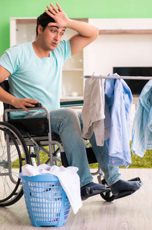 Disabled man on wheelchair doing laundryの写真素材