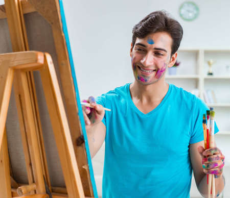 Young funny artist working on new painting in his studioの写真素材