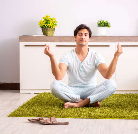 Young man doing yoga in bedroomの写真素材