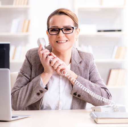 Businesswoman employee talking on the office phoneの写真素材