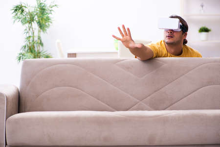 Young man with virtual reality glasses at homeの写真素材