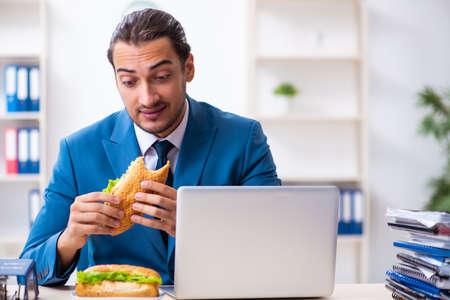 Young male employee having breakfast at workplaceの写真素材