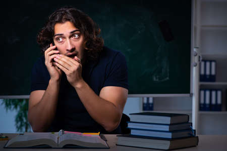 Young male student in the classroom at nightの写真素材