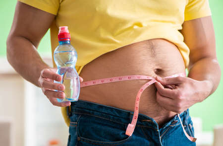 Man measuring body fat with tape measure in dieting concept