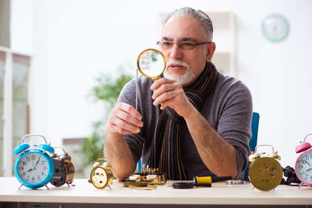 Old male watchmaker working in the workshop