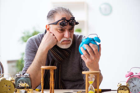 Old male watchmaker working in the workshop