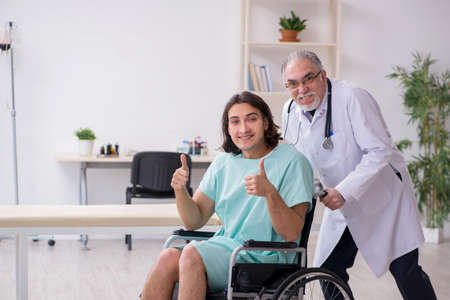Young male patient in wheel-chair and experienced doctor traumatologistの写真素材