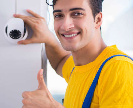 Contractor installing surveillance CCTV cameras in officeの写真素材