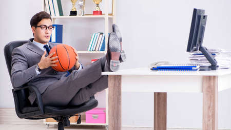 Young businessman playing basketball in office during breakの写真素材