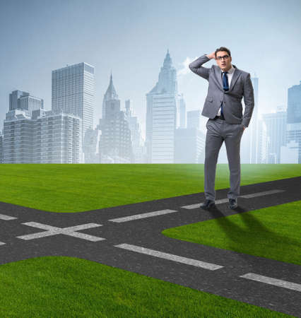 Young businessman at crossroads in uncertainty conceptの写真素材