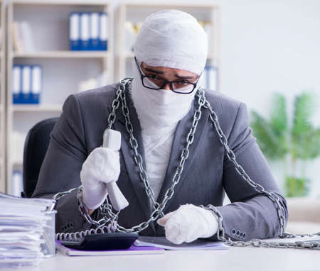 Bandaged businessman worker working in the office doing paperworの写真素材
