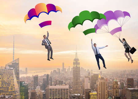 Business people falling down on parachutesの写真素材