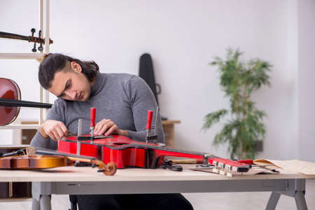 Young male repairman repairing guitarの写真素材