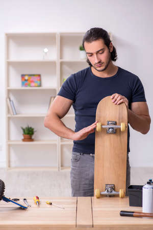 Young male repairman repairing skateboardの写真素材