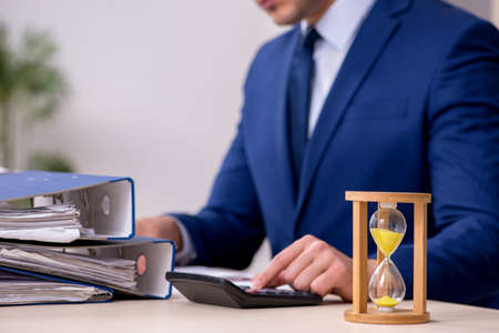 Young male employee in time management conceptの写真素材