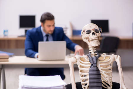 Young male employee with skeletons in the officeの写真素材