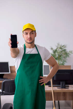 Young male contractor cleaning the officeの写真素材