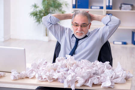 Old businessman rejecting new ideas with lots of papersの写真素材