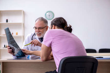 Old doctor radiologist examining young male patientの写真素材