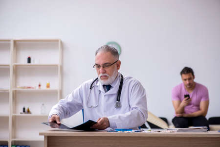 Old doctor radiologist examining young male patientの写真素材