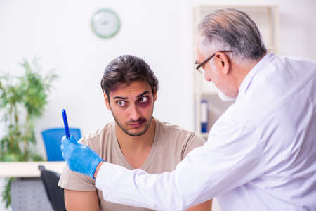 Young face injured man visiting experienced male doctor traumatoの写真素材