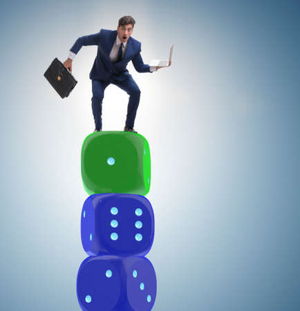 Businessman balancing on top of dice stack in uncertainty concepの写真素材