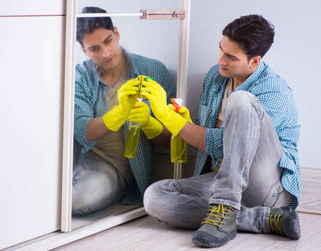 Young man cleaning mirror at home hotel
