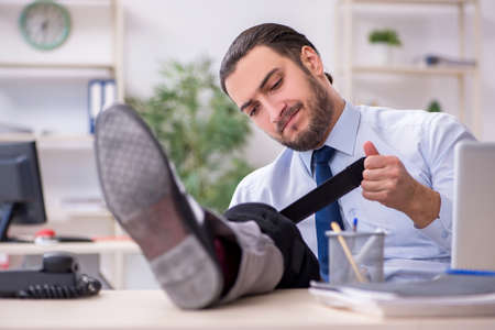 Young leg injured employee working in the officeの写真素材