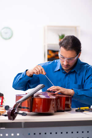 Young male repairman repairing celloの写真素材