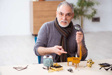 Old male watchmaker working in the workshopの写真素材