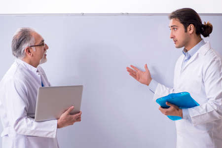 Experienced doctor teaching young male assistant using computerの写真素材