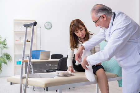 Young injured woman visiting experienced doctor traumatologistの写真素材