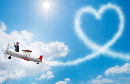 Man flying airplane and making heart shapeの写真素材