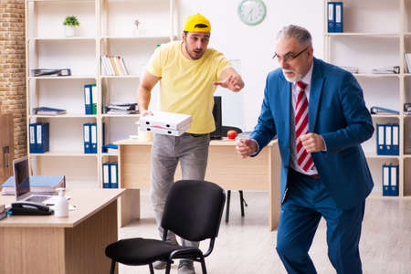 Young male courier delivering pizza to the officeの写真素材