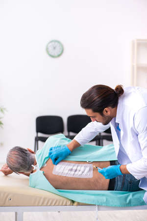 Old man visiting young male doctorの写真素材