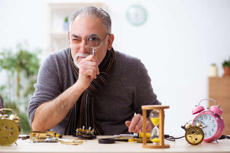 Old male watchmaker working in the workshop