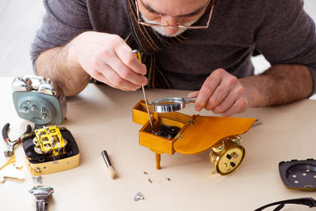 Old male watchmaker working in the workshop