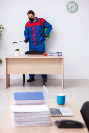 Young male contractor disinfecting officeの写真素材