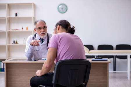 Young male patient visiting old male doctorの写真素材