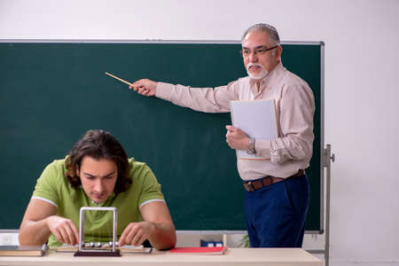 Old professor physicist and young student in the classroom