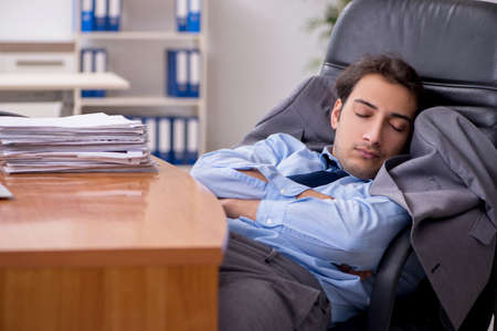 Young male employee sleeping in the office