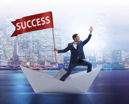 Businessman riding paper boat ship in success conceptの写真素材