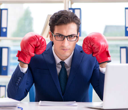 Businessman with boxing gloves angry in officeの写真素材