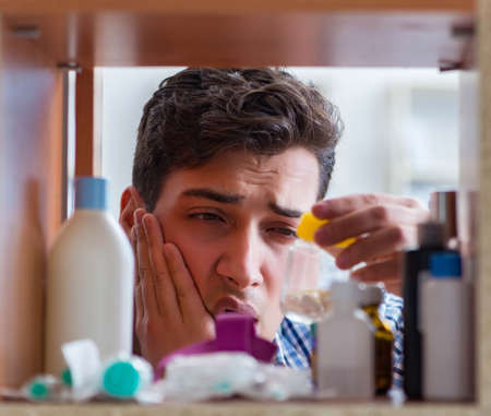 Sick ill man looking for medicines at farmacy shelfの写真素材