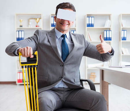 Businessman exercising with elastic expander wearing VR glassesの写真素材
