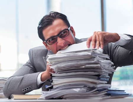 Busy angry businessman with heaps of paperの写真素材