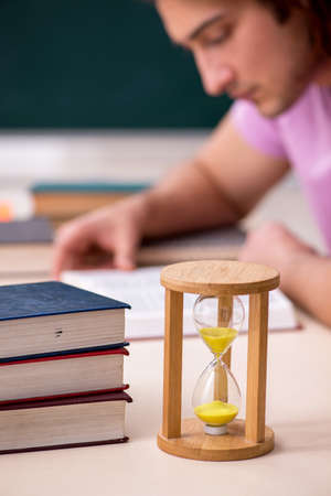 Young male student in the classroom at time management concept