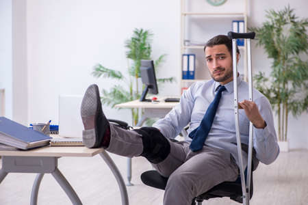 Young leg injured employee working in the officeの写真素材