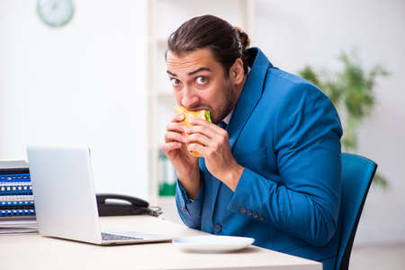 Young male employee having breakfast at workplaceの写真素材