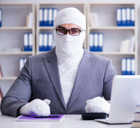 Bandaged businessman worker working in the office doing paperworの写真素材